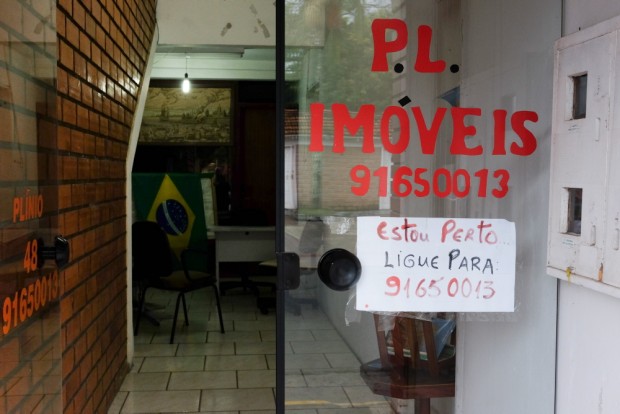 Placa colocada em porta de imobiliária, na região central da cidade de Praia Grande, SC  . Foto Joel Silva / Folhapress. 